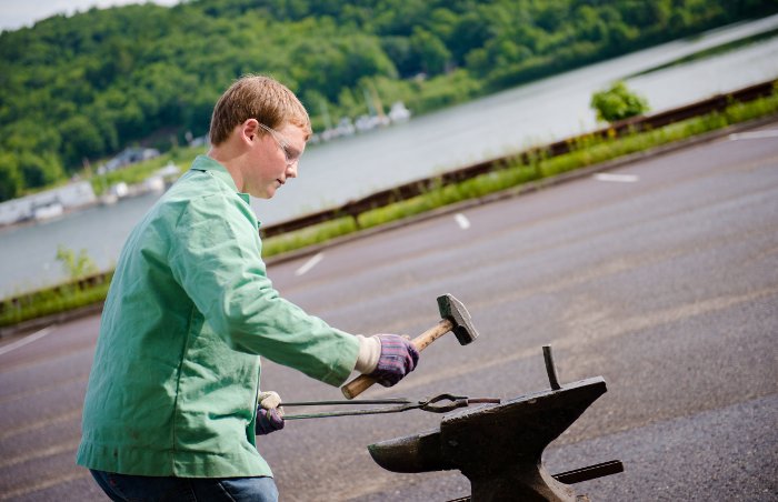 Carson Williams works on a red-hot iron rod as part of SYP's blacksmithing exploration.