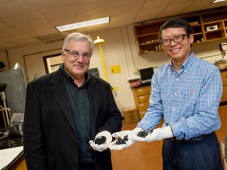 David Hand, left, and Zhanping You hold samples of crumb rubber and chunks of rubber made from recycled tires. They are leading studies to help determine if asphalt made with crumb rubber could be used on Michigan roads. Sara Bird photo