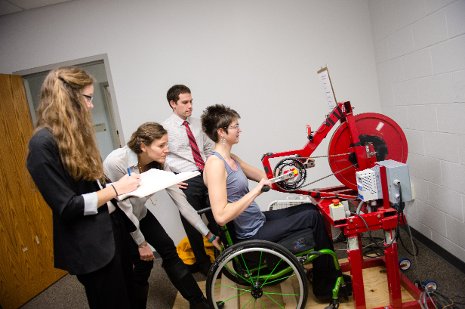 Researchers watching patient use the arm cycle.