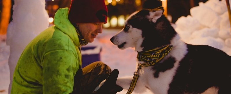 young man and husky dog by snow statue