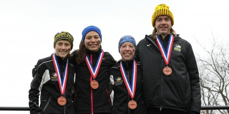 Four members of Michigan Tech’s cross country running team wearing medals.