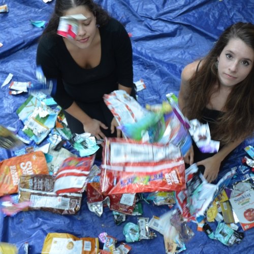 foil wrappers float around two young women on a blue tarp outside