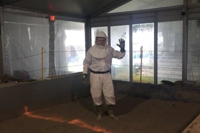 man in haz mat suit standing on gray dust