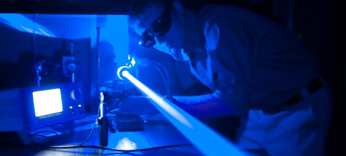 Researcher looking down a laser with goggles