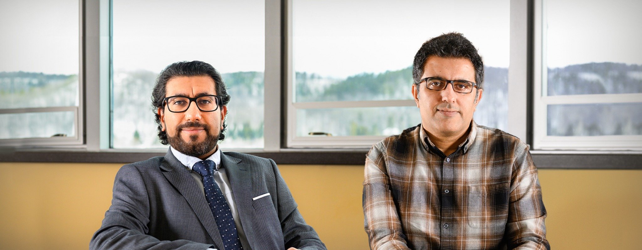 Dr. Hassan Masoud and Dr. Radwin Asgari sit together as CAREER Award Winners with the beautiful and snowy Houghton valley in the windows behind them.