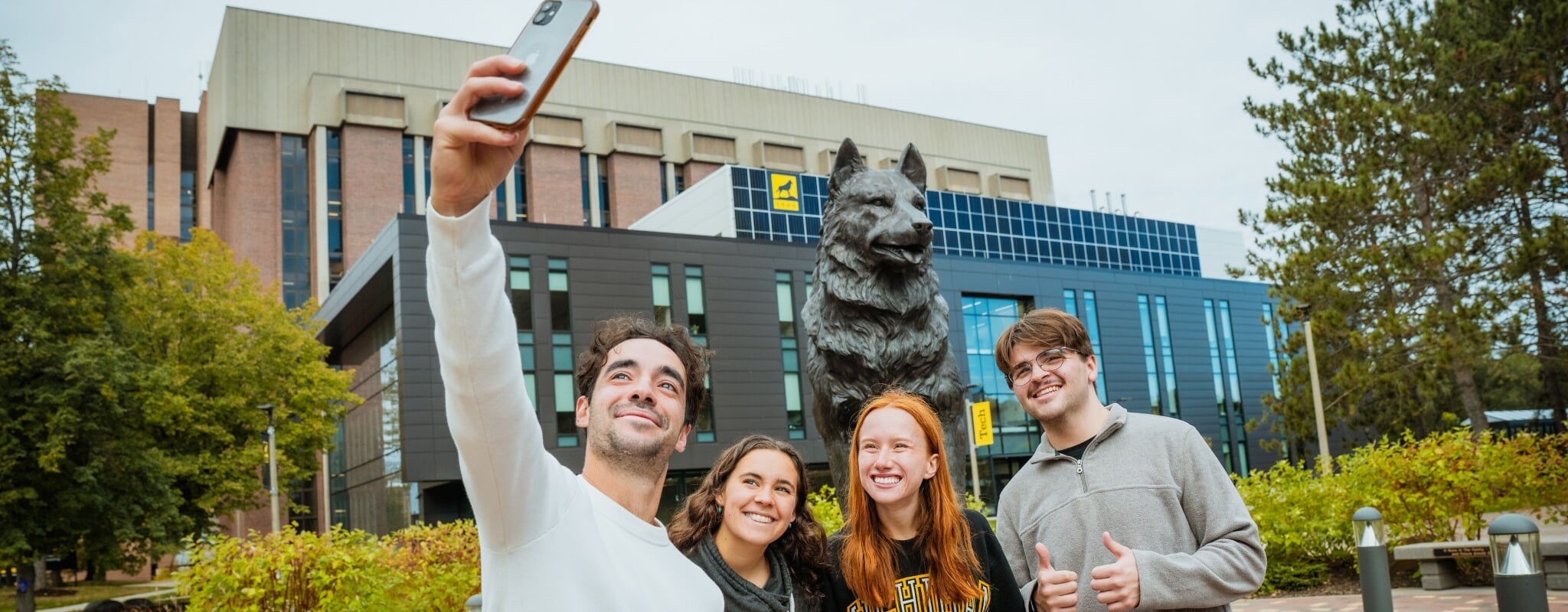 Students take a selfie with the Husky Statue