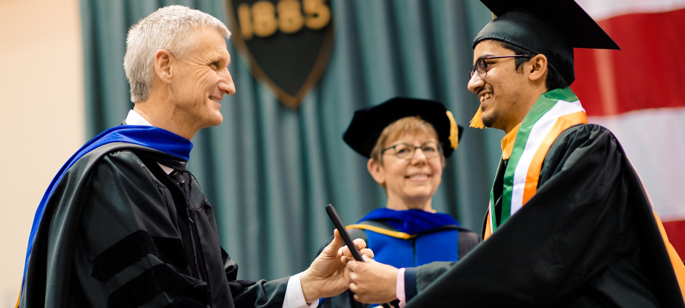 President Koubek shaking the hand of a graduate. 