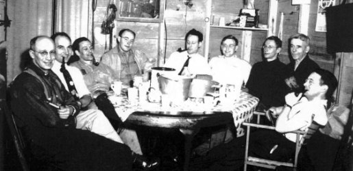 Nine faculty sitting at a round table, some with pipes.