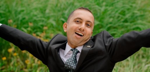 Student, wearing a dress shirt and tie, does a jumping split.