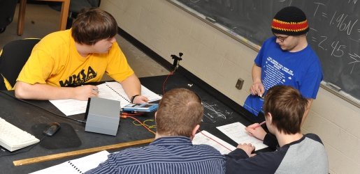 Four students work on completing a Physics lab report.