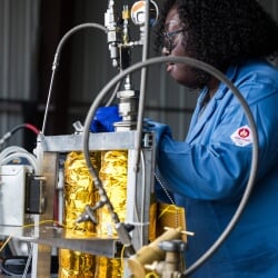 A student in lab safety gear works on a pyrolysis machine demo.