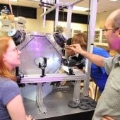 Dr. Will Cantrell explaining to students around a small cloud machine with a created cloud inside.