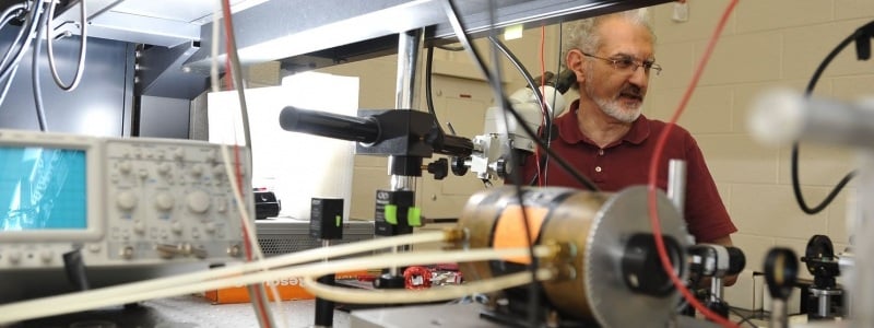 Miguel Levy standing next to a research machine in photonics