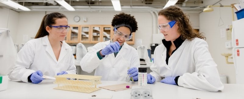 Three pre-health students working on an experiment in a lab