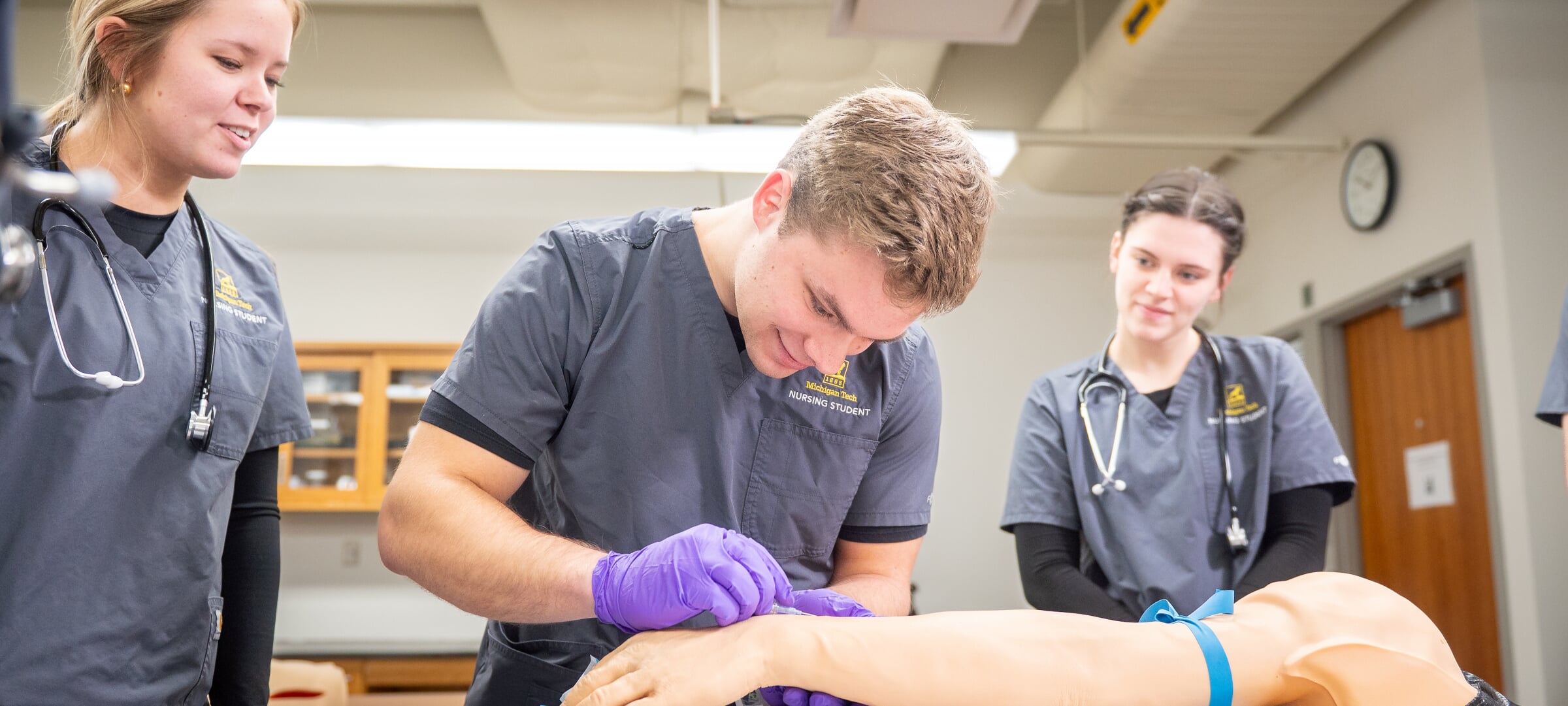 Two students practice vaccinations under the guidance of an instructor