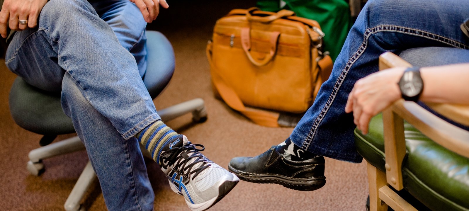 Image of two students sitting crossed-legged in chairs across from each other.