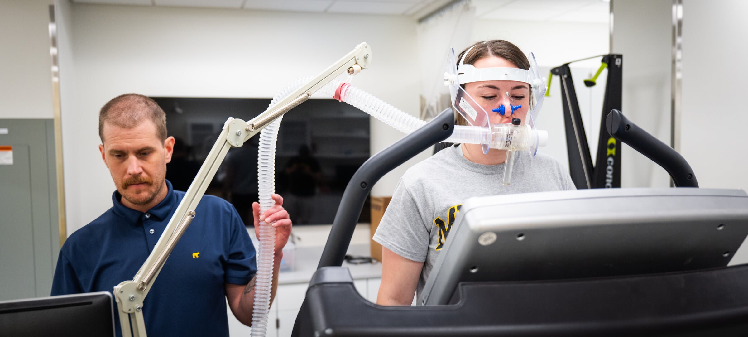 Researcher monitoring results on a computer while student has air apparatus on while walking on a treadmill