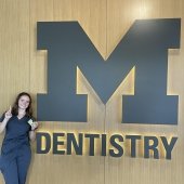 Image of Michigan Tech pre-dental graduate Molly in front of University of Michigan Logo where she is getting her DDS