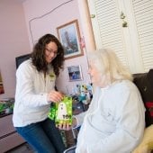 Student handing a halloween bag to an elderly woman