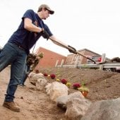 Student shoveling dirt into a flower bed