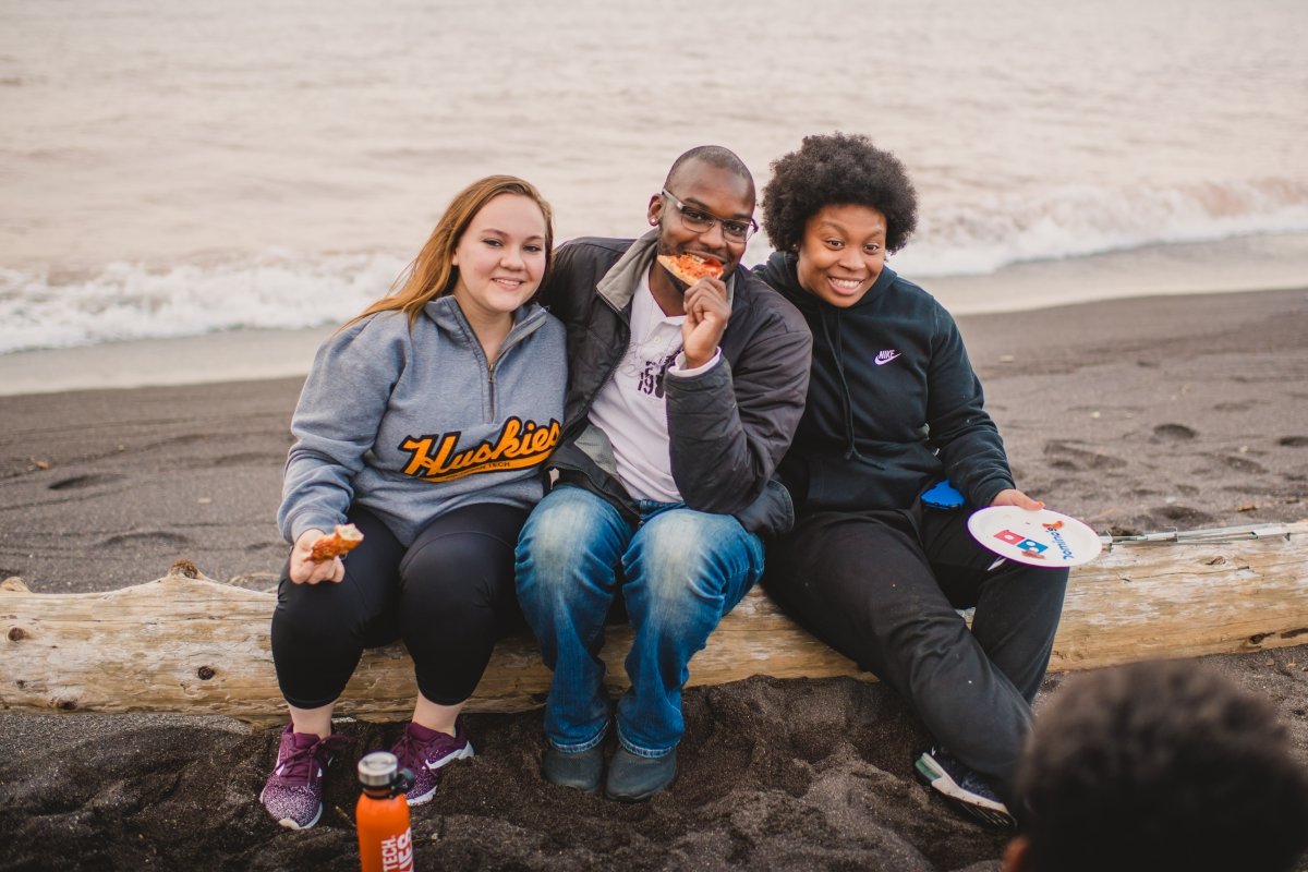 Tour the beautiful shorelines of Lake Superior and make long-lasting friendships. Three students sitting on a log along the shore.