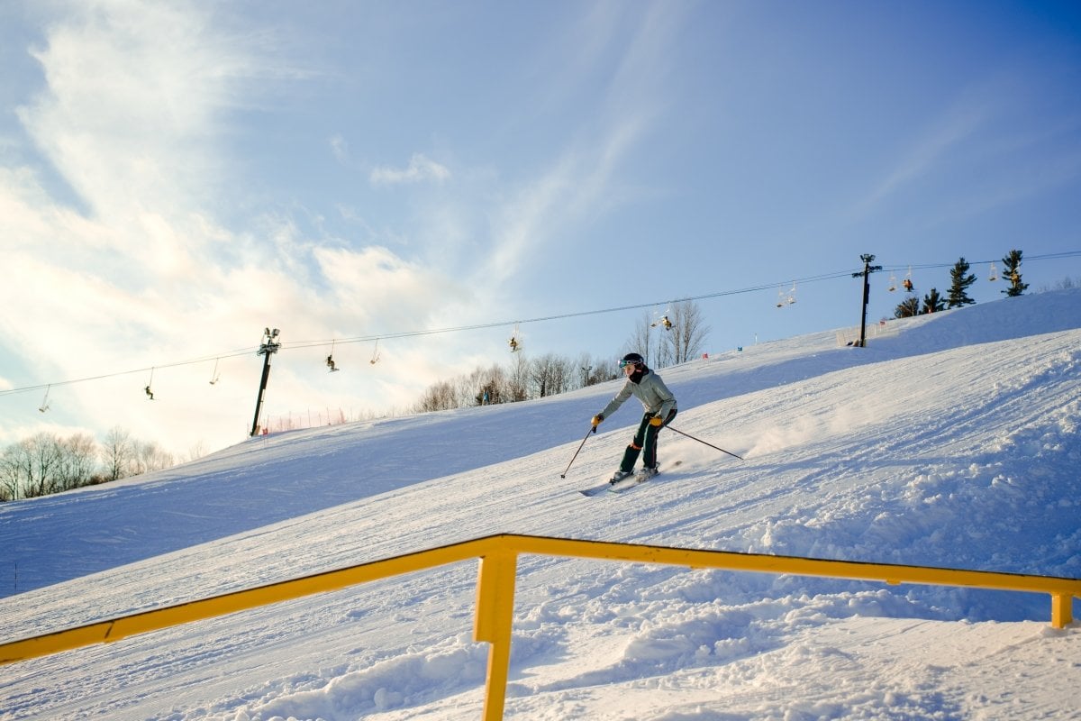 Mont Ripley Ski Area has twenty-four trails, a terrain park, and more. Skier going down Mont Ripley with the chair lift in the background.