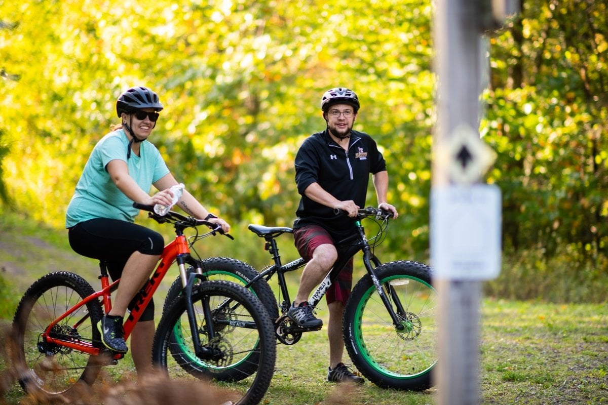 Our Tech Trails span 35 kilometers for biking, cross-country skiing, and more. Two people riding bikes on the Tech Trails.
