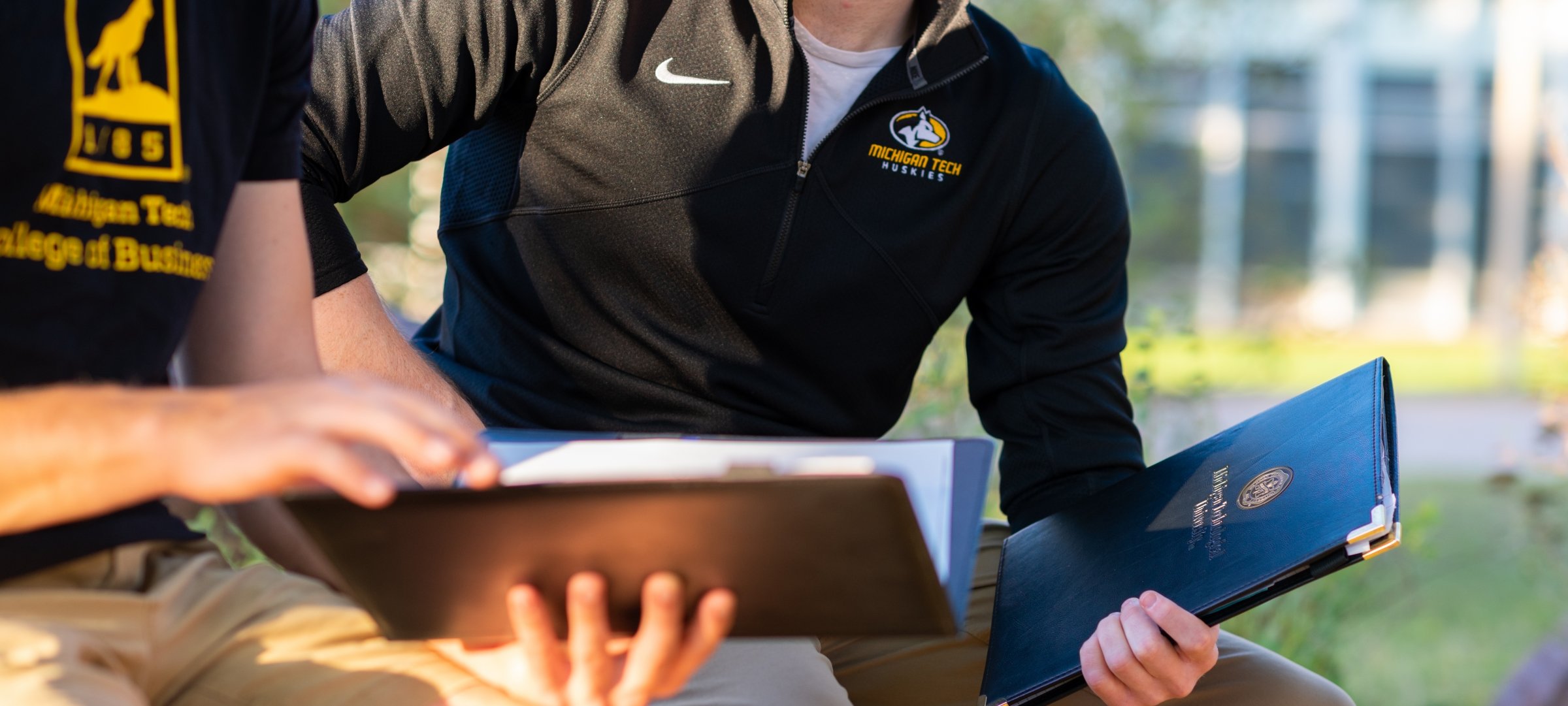 Two students with MTU shirts and folders.