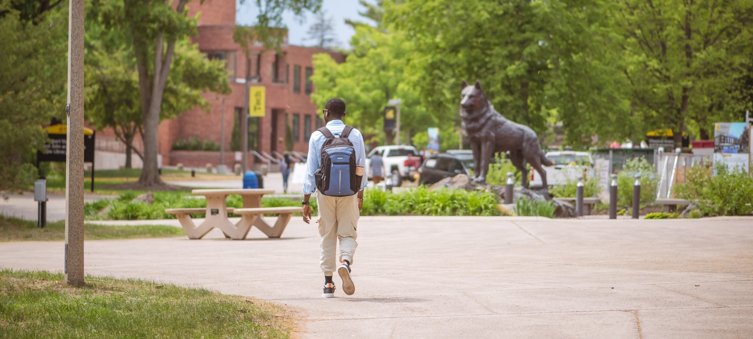 Student walking on Michigan Tech's campus near the Husky statue.