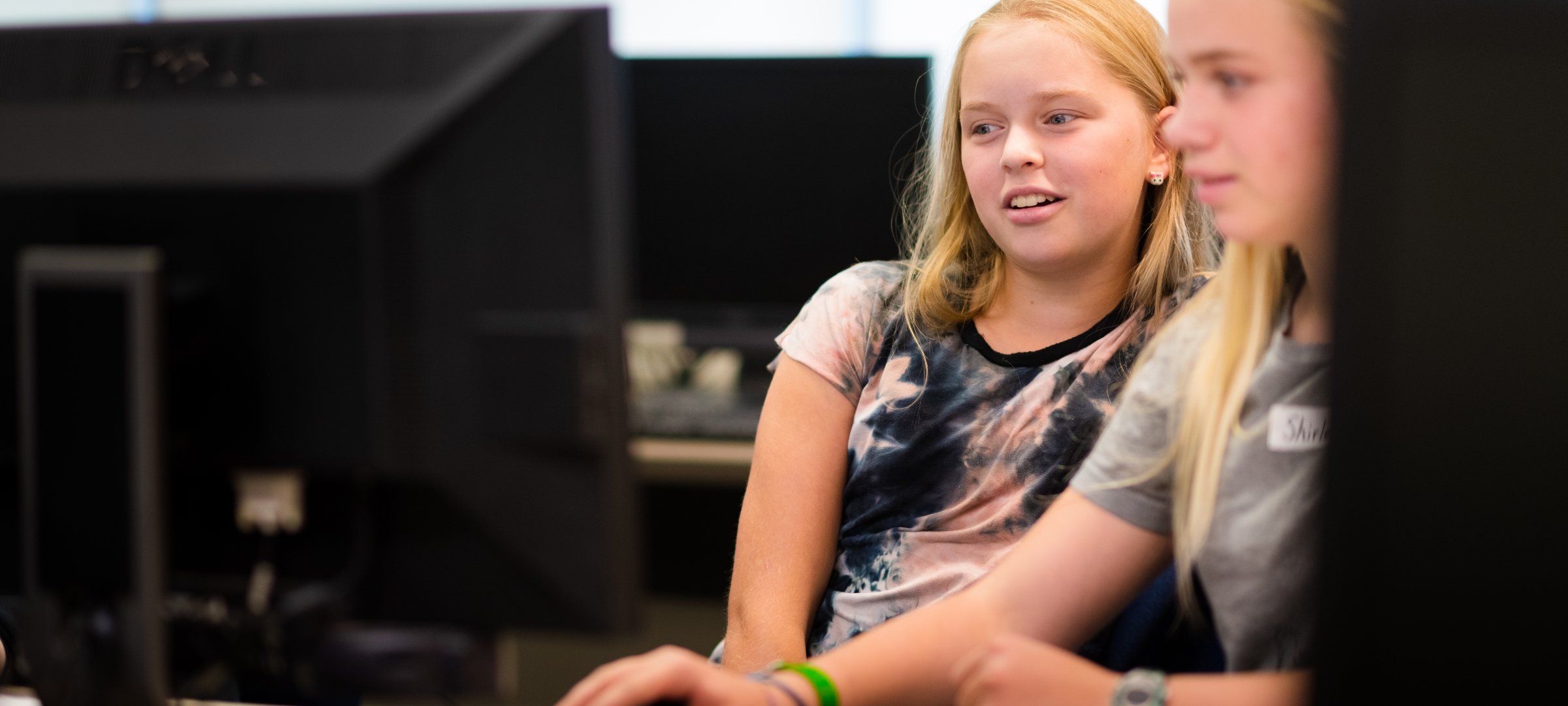 Two girls look at a computer