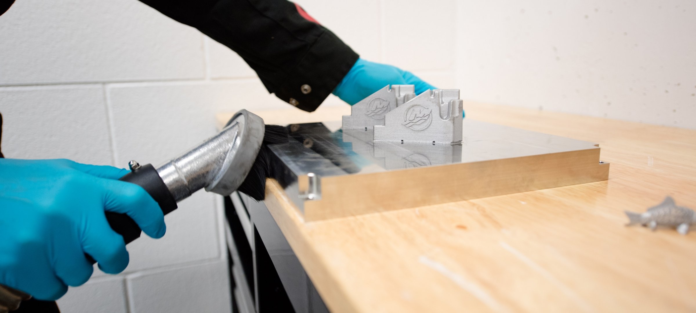 An individual using a brush on a metal printer