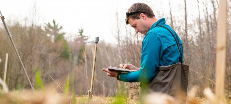 A man holding a clipboard outside doing field research
