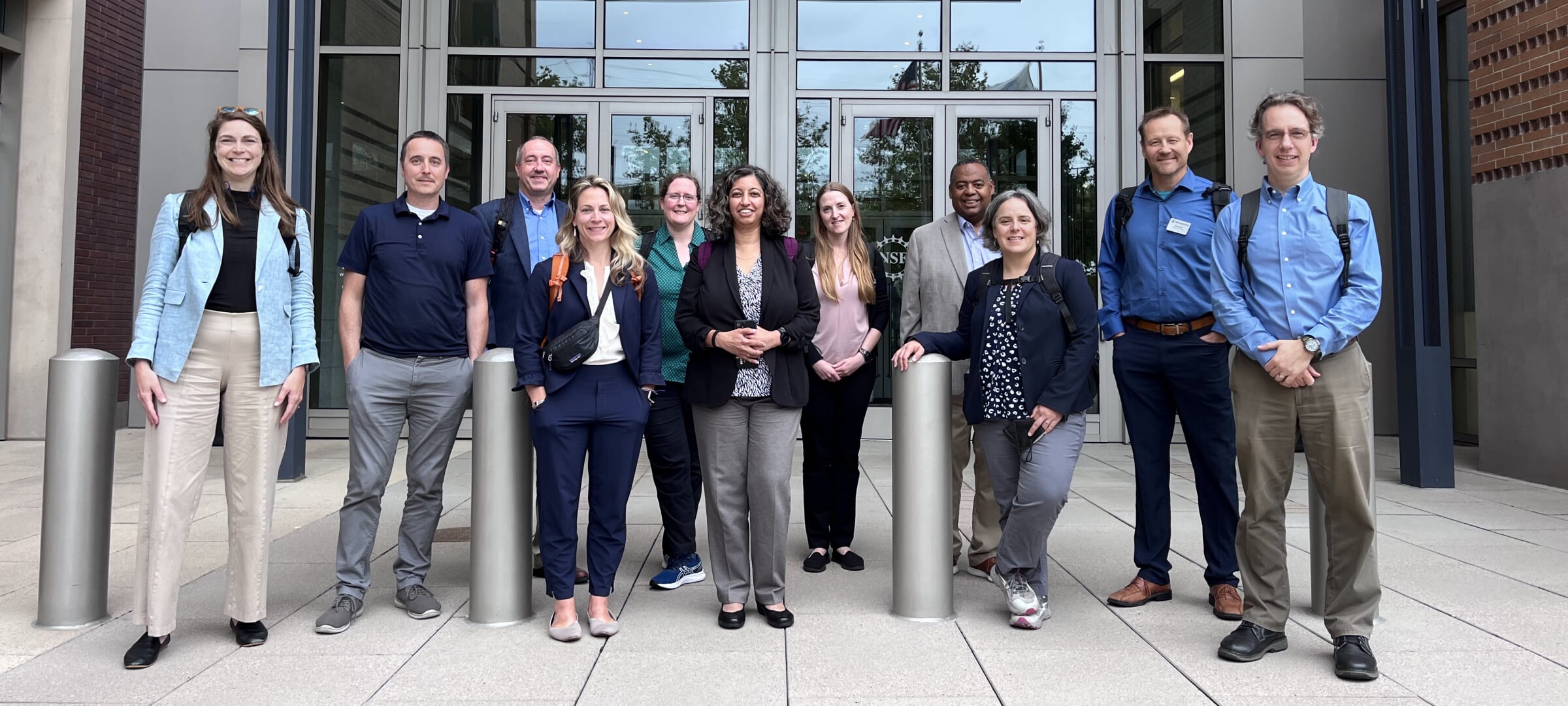 Research development standing with faculty outside a building