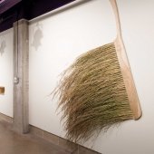 Tipping point exhibit with large brush and carved wooden spoons on a table.