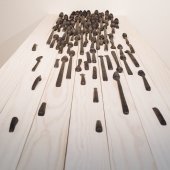 Hand carved wooden spoons lined in rows, cascading, on a wooden table - view from above.