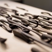 Hand carved wooden spoons lined in rows, cascading, on a wooden table - zoomed view on the side