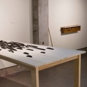 Hand carved wooden spoons lined in rows, cascading, on a wooden table - wide view from side.