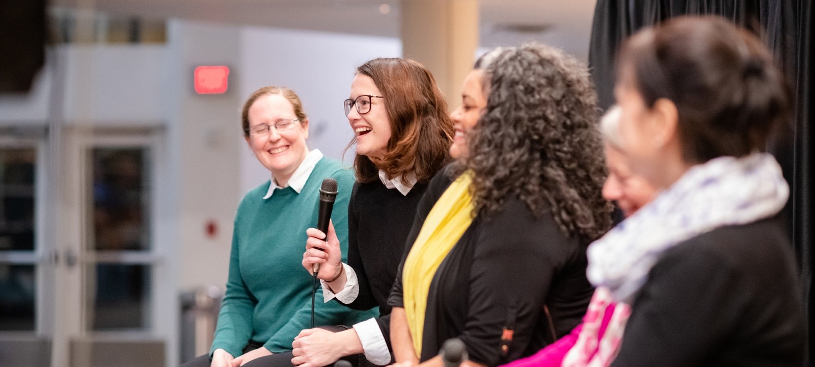 Five presenters speak in the Rozsa Center Lobby.