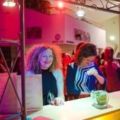 Two event goers standing at the bar where drinks are being served.