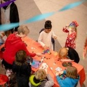 Several children working on arts and crafts around a table.