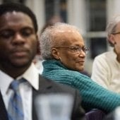 A group of seated guests look on.