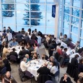 Wide angle from above of seated guests at round and straight tables.