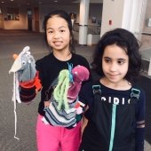 Two girls show off the puppets they've created.