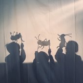 Children perform a play with their puppets in the shadow puppet theatre.