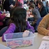 A mother with her two daughters coloring.