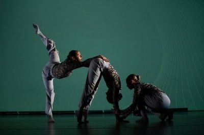 Three dancers in motion in a modern dance performance