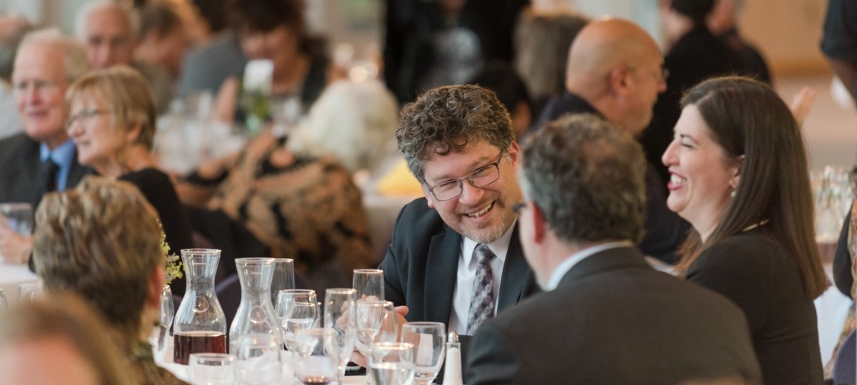 Guests chat and laugh during a seated dinner in the Rozsa lobby