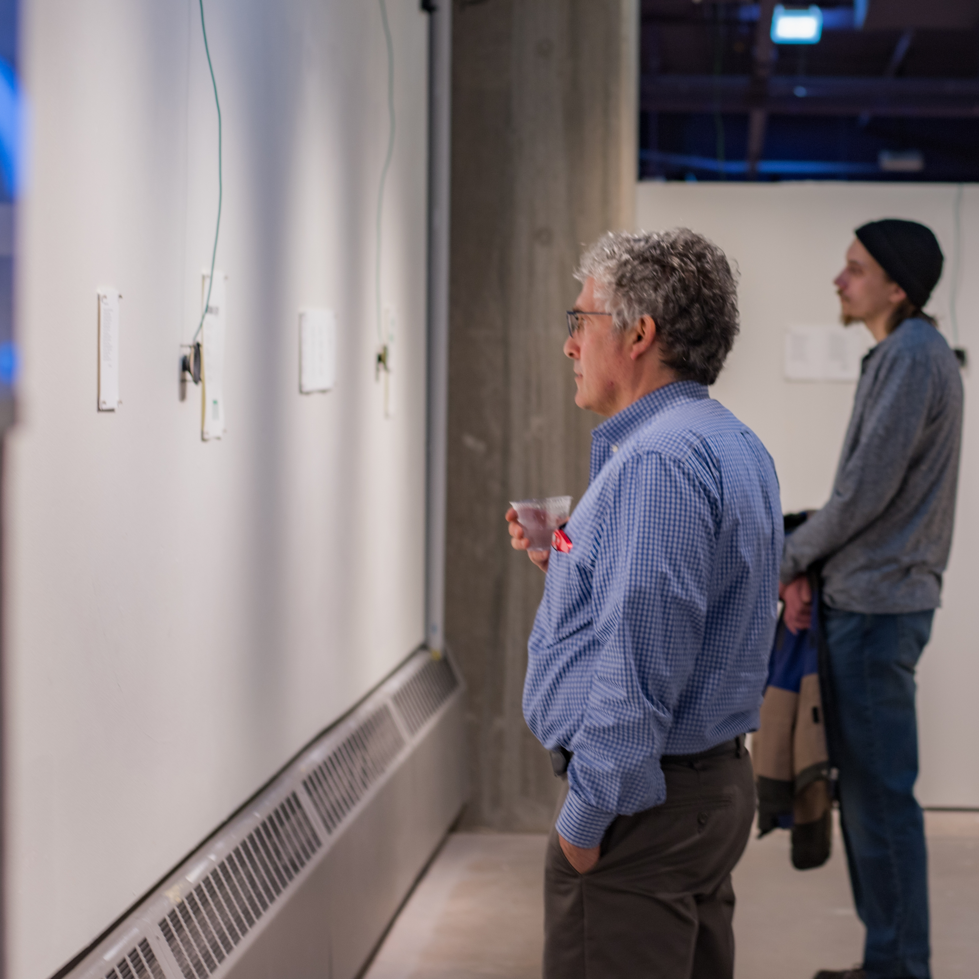 Two people look at art on a gallery wall.