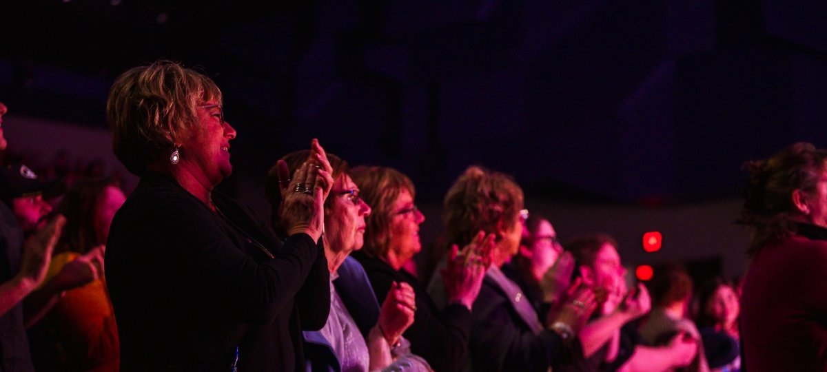 Audience giving a standing ovation in a dark theatre