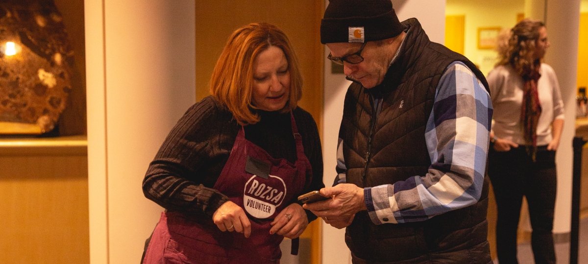 A member of the Volunteer Squad helps a guest with something on their phone